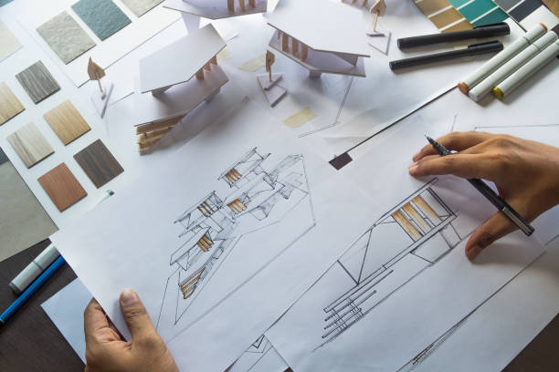 istock architect design working drawing sketch plans blueprints and making architectural construction model in architect studio 1191893192