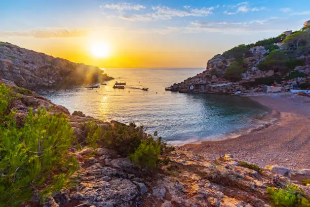 View of the cove of Cala Carbó in the south-west of Ibiza, a quiet sunset, anchored boats, the gentle splashing of the waves on the shore. Developed from RAW.