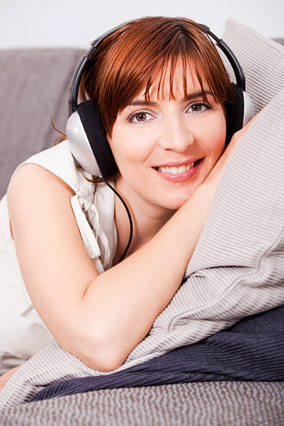 Beautiful young woman at home listening music with headphones