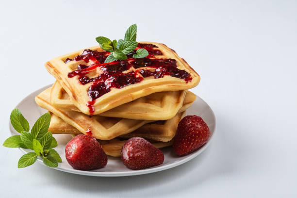 istock Homemade waffles with mint and strawberries in plate on white table 1191894608