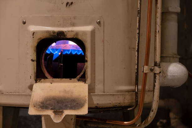 fragment d'une vieille chaudière de chauffage au gaz blanc. il y a des raccords métalliques et des tuyaux. une fenêtre ouverte montre une flamme bleue sur le brûleur. fond. - flame natural gas boiler burner photos et images de collection