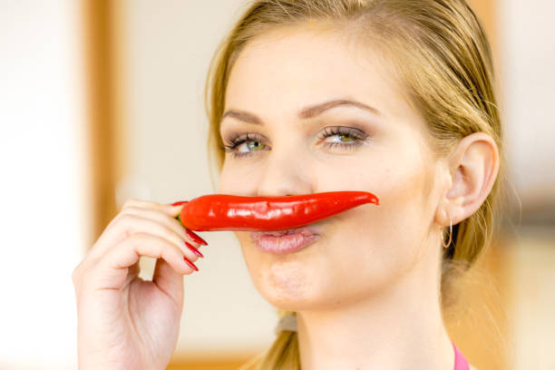 Funny woman holding red chilli hot pepper paprika pretending its moustaches. Spicy food, oriental seasonings concept.