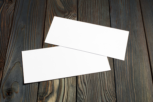 Two blank cards or papers (business cards, tickets, flyers, invitations, coupons, banknotes, etc.) on dark wooden background