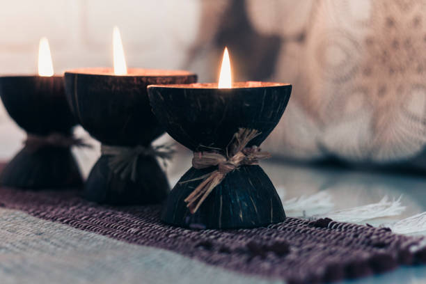 istock Burning spa aroma candle in coconut shell on a knitted multicolored rug and gray curtains opposite the white wall, cozy home interior 1191900428