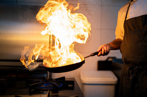 Chef preparing flame meal using pan in a commercial kitchen