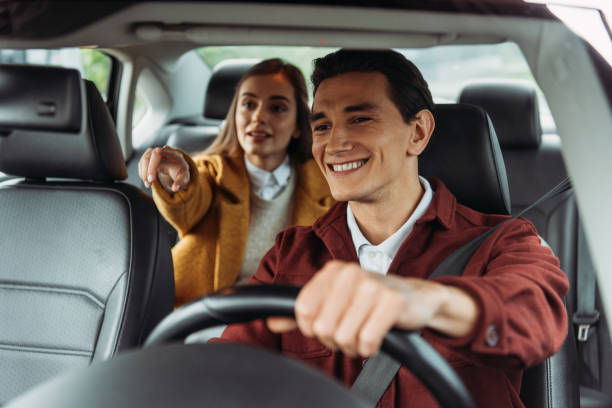 Smiling taxi driver with woman passenger pointing on road Smiling taxi driver with woman passenger pointing on road taxi driver photos stock pictures, royalty-free photos & images