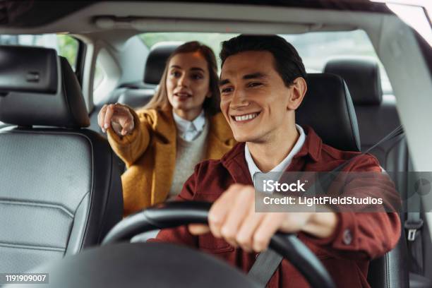 Smiling Taxi Driver With Woman Passenger Pointing On Road Stock Photo - Download Image Now