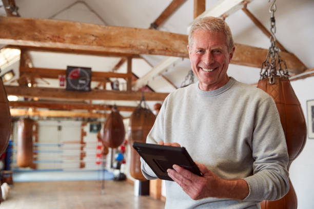 retrato de entrenador de boxeo masculino sonriente en el entrenamiento de seguimiento de gimnasio usando la tableta digital - boxing caucasian men business fotografías e imágenes de stock