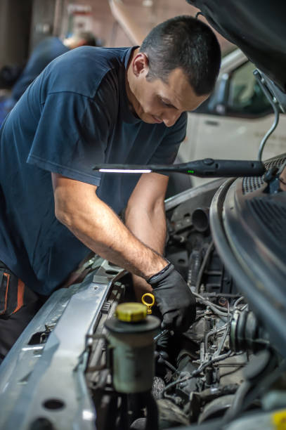 istock Car mechanic repairer service technician checks and repairs auto engine 1191912894