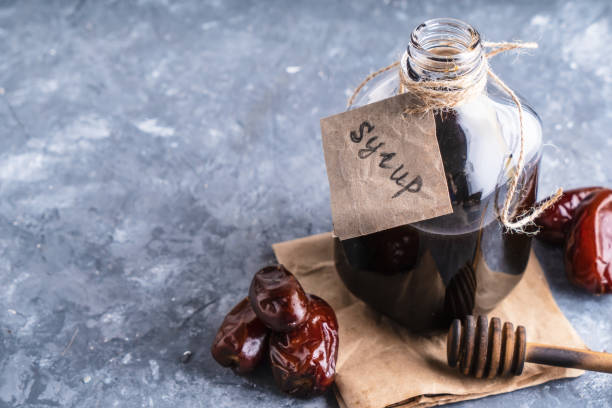 Homemade dates syrup in glass bottle on gray stone table. Alternative food and drink Trend food 2020. Copy space. Homemade dates syrup in glass bottle on gray stone table. Alternative food and drink Trend food 2020. Copy space date syrup stock pictures, royalty-free photos & images