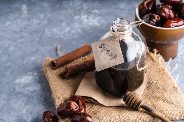 Homemade dates syrup in glass bottle on gray stone table. Alternative food and drink Trend food 2020. Copy space