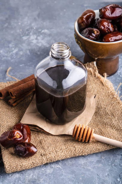 Homemade dates syrup in glass bottle on gray stone table. Alternative food and drink Trend food 2020. Copy space. Homemade dates syrup in glass bottle on gray stone table. Alternative food and drink Trend food 2020. Copy space date syrup stock pictures, royalty-free photos & images