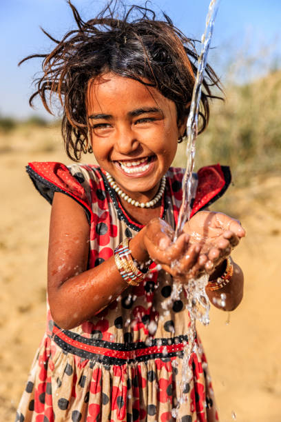 Indian little girl drinking fresh water, desert village, Rajasthan, India Indian little girl is drinking fresh water, desert village, Thar Desert, Rajasthan, India. Potable water is very precious on the desert - Rajasthani women and children often walk long distances through the desert to bring back jugs of water that they carry on their heads. thar desert stock pictures, royalty-free photos & images