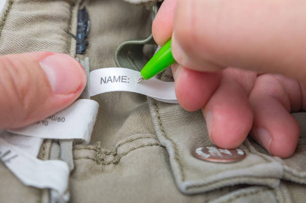 Man fills the Name label on children's jeans. stock photo
