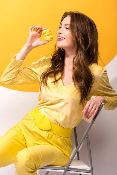 istock happy woman holding macarons while sitting on orange and white 1191918670