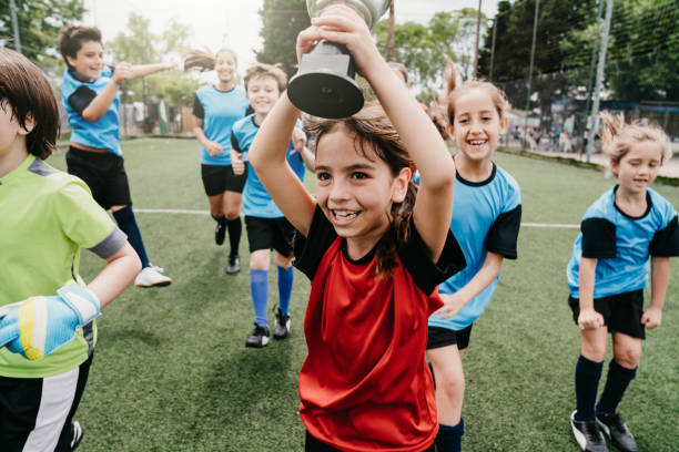 gruppo di ragazzi che festeggiano insieme la vittoria di una competizione in corso su un campo da calcio - young team foto e immagini stock