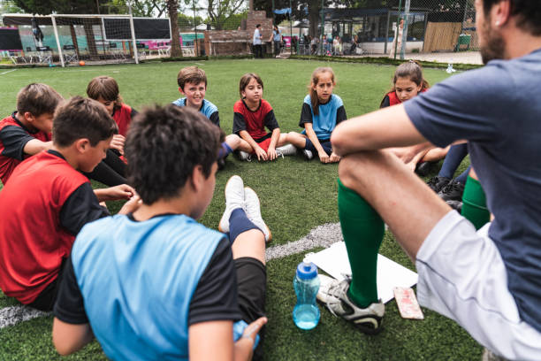 coach explaining the strategy for the soccer competition to a team of kids sitting in circle - youth league imagens e fotografias de stock