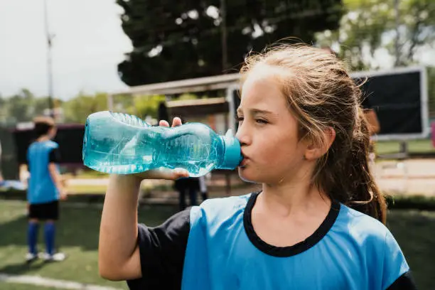 Photo of Portrait of a cute girl drinking water during a soccer training