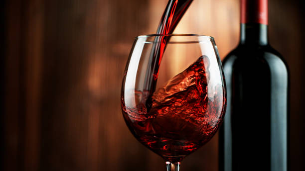 Detail of pouring red wine into glass Detail of pouring red wine into glass, dark wooden background. Free space for text wine glass knocked over stock pictures, royalty-free photos & images
