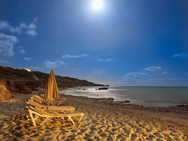 The full moon illuminates the deserted beach.
