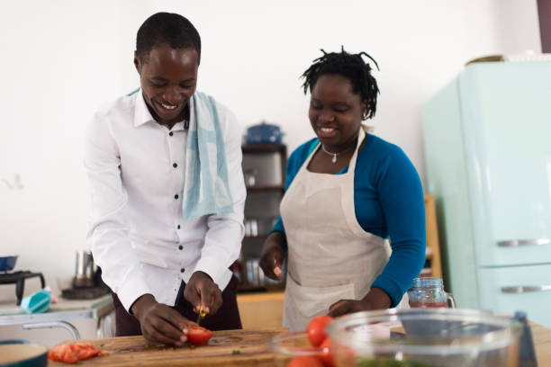 istock Young husband helping wife cutting tomatoes in the kitchen 1191929527