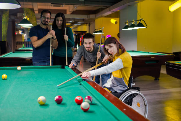 Disabled girl in a wheelchair playing billiards stock photo