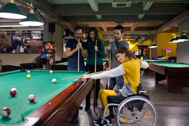 Disabled girl in a wheelchair playing billiards stock photo