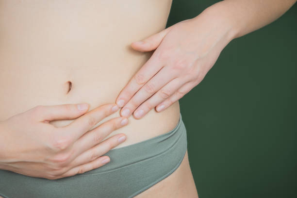 woman holding hands near panties in the area of reproductive organs on green background. - ovary imagens e fotografias de stock