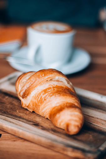 Freshly baked croissant in caffee on wooden background