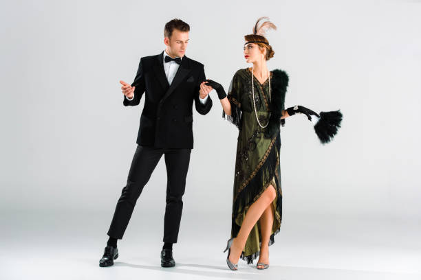 istock stylish man in suit and aristocratic woman holding hands while dancing on grey 1191932344