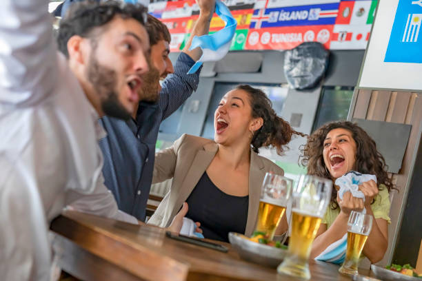 istock Four young people watching soccer game in pub cheering 1191933889
