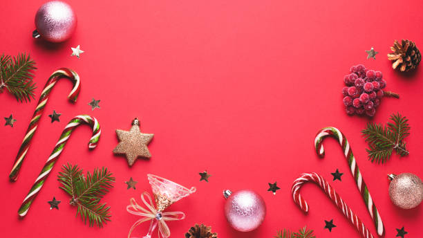 istock Christmas baubles, golden decorations, candy canes, pine tree, cones and confetti frame on red background. Festive Christmas border with golden elements. Flat lay, top view, copy space 1191935412