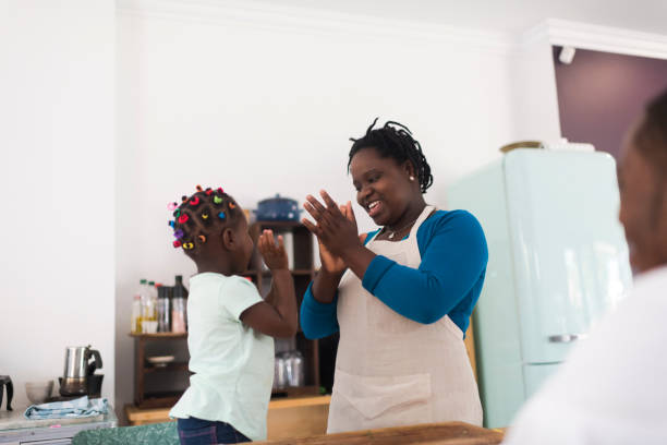 istock Happy mother and daughter clapping hands playfully in the kitchen 1191937332