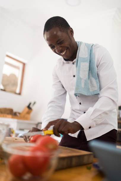 istock Low angle view of a smiling man cutting tomatoes in the kitchen 1191937448