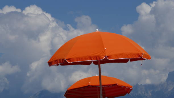 istock Orange Parasol against a blue cloudy sky. 1191944825