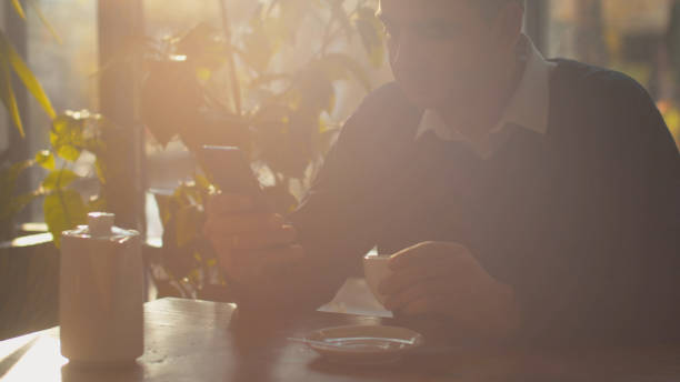 istock Man drinks tea with phone in hand in a cafe 1191945228
