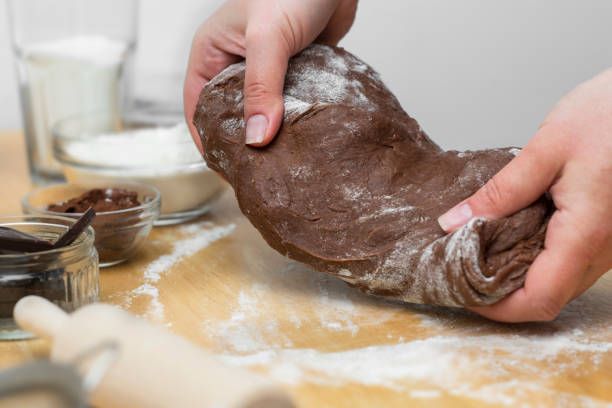 Woman hands kneading chocolate dough, cooking cookies or dessert. Cooking at home.
