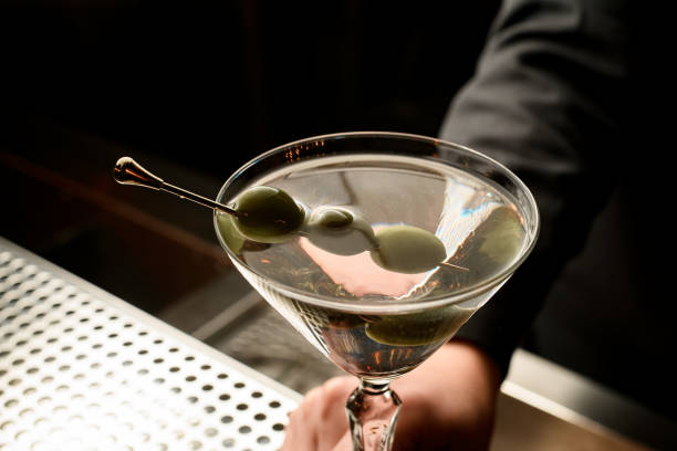 istock Female bartender serving transparent cocktail based on martini decorated with olives on the skewer 1191951964