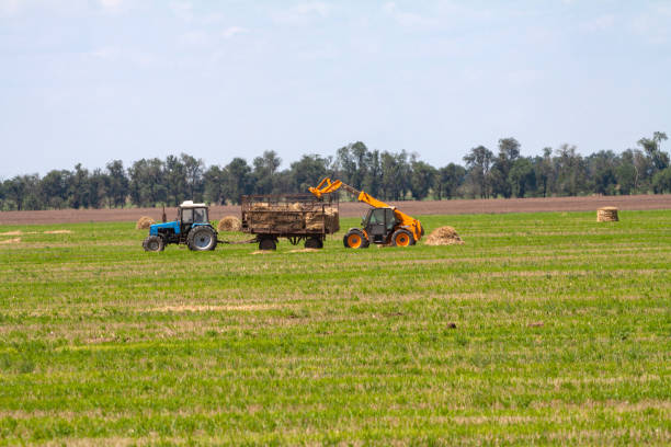 istock Tractor loading hay bales on truck agricultural works 1191952328