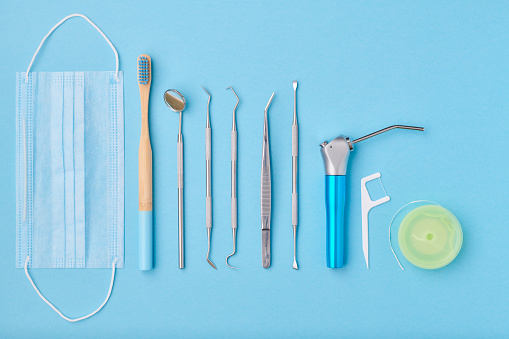 Dentist tools over light blue background top view flat lay. Tooth care, dental hygiene and health concept.