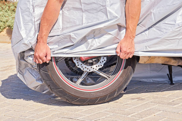 moto da esterno parcheggiata ricoperta di scudo protettivo in tessuto dalla pioggia e dal surriscaldamento - rust covered foto e immagini stock