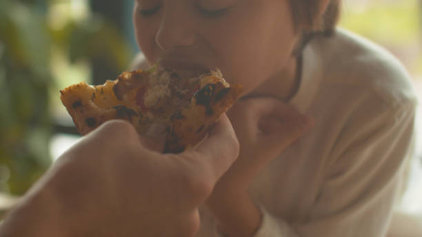 istock Little boy eats pizza at lunch in a cafe 1191955245