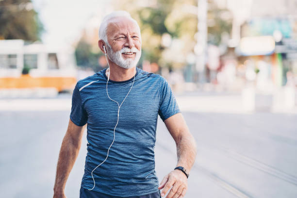 улыбающийся старший спортсмен, идущего по улице - beard senior men looking away smiling стоковые фото и изображения
