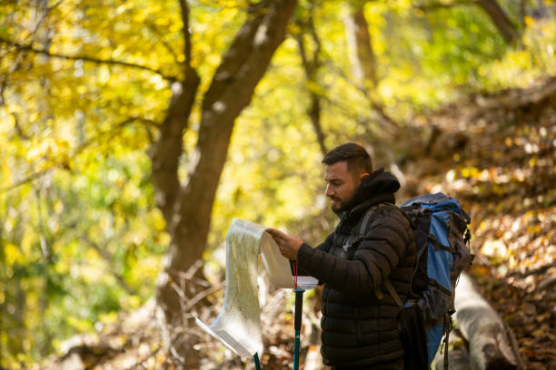 istock Determined young man holding a map and looking into distance, hiking in forest 1191959110