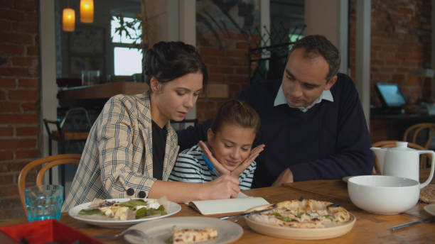 istock Parents and daughter write something together in notebook 1191962491