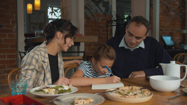 istock Family lunch, parents help thier daughter to write something 1191963102