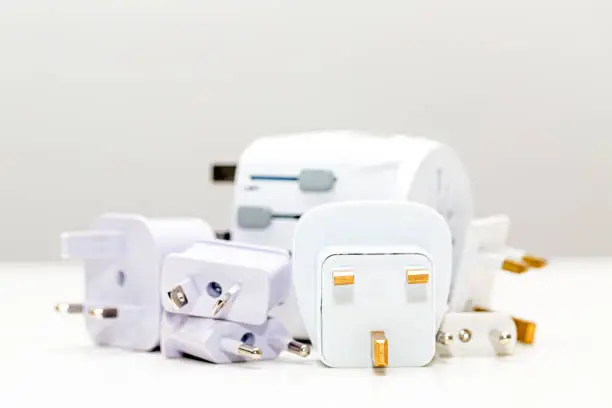 Pile of various international travel power plug adapters in different types and sizes