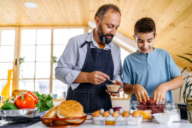 Getting in on dinner preparation Father and son preparing ingredients for burgers, mixing minced meat in bowl and spices in the kitchen ground beef photos stock pictures, royalty-free photos & images