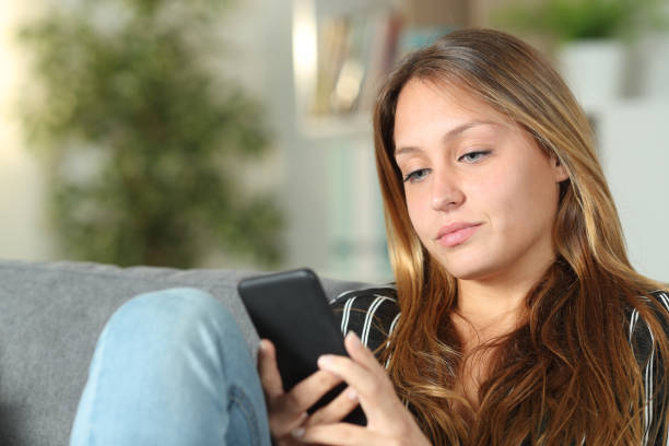istock Serious woman using mobile phone on a sofa at home 1191967054