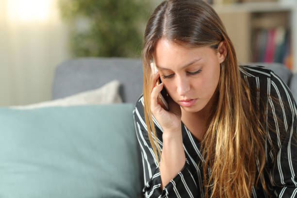 istock Serious woman talking on phone on a sofa at home 1191967146